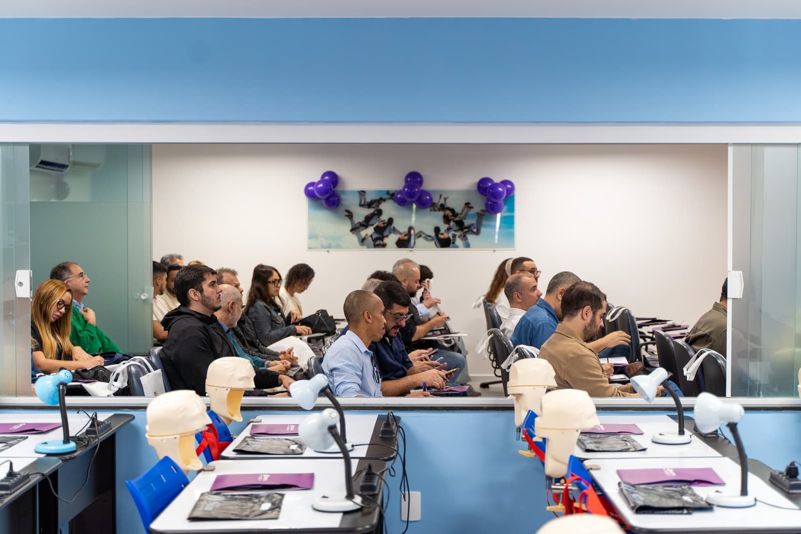Turma em aula teórica, com as bancadas do laboratório em primeiro plano